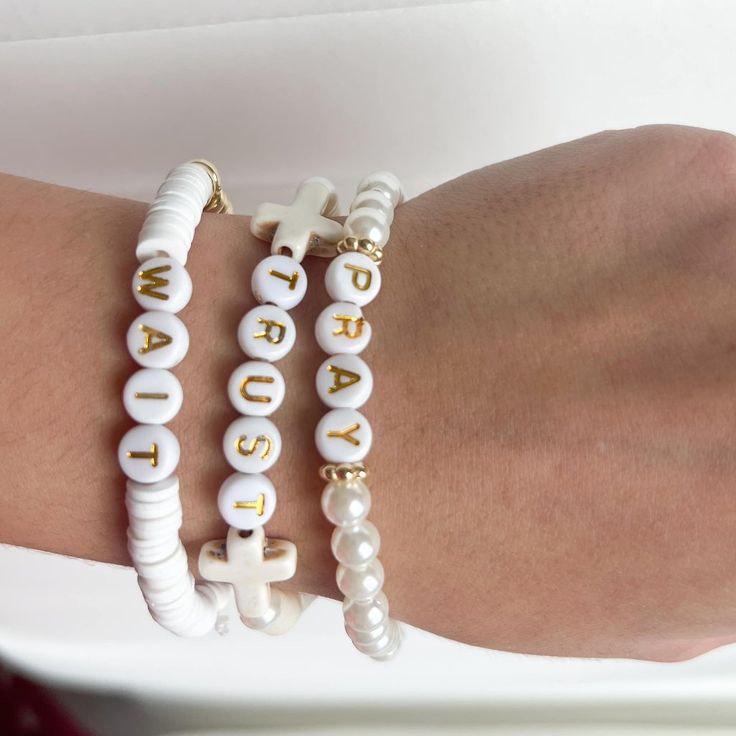 two white bracelets with gold letters and pearls on the wrist, one is personalized