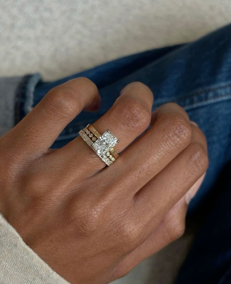 a woman's hand with a gold and diamond ring on her left wrist, wearing a blue jean jacket