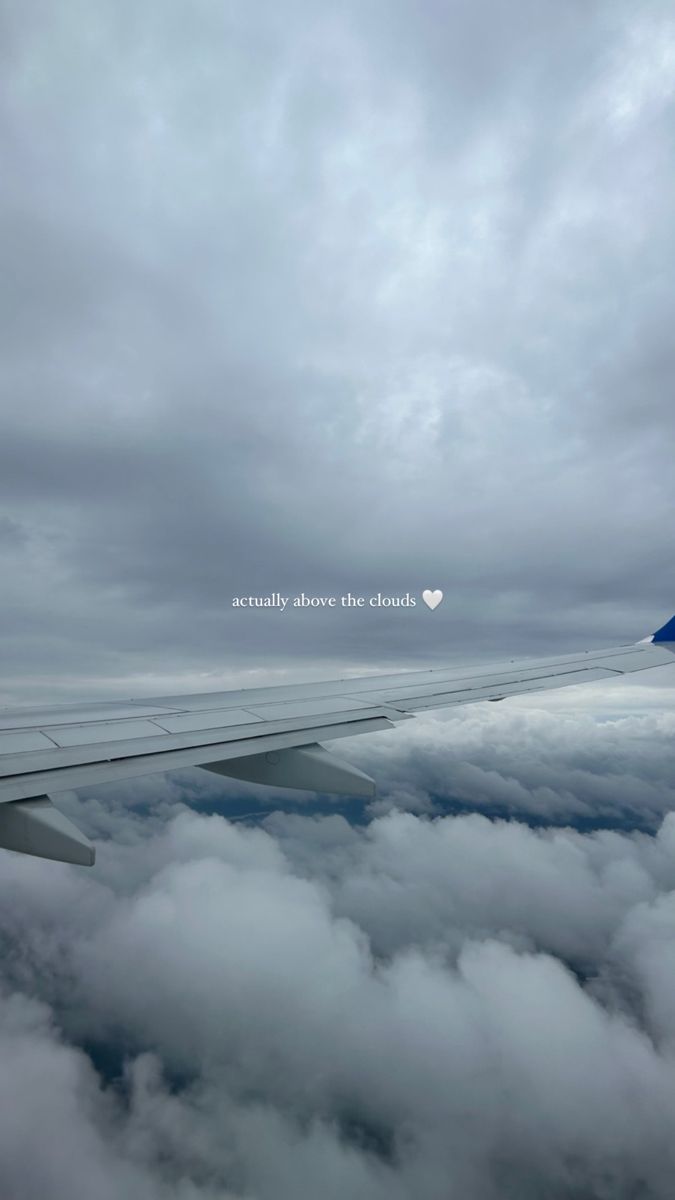 the wing of an airplane flying over clouds with a heart shaped window on it's side