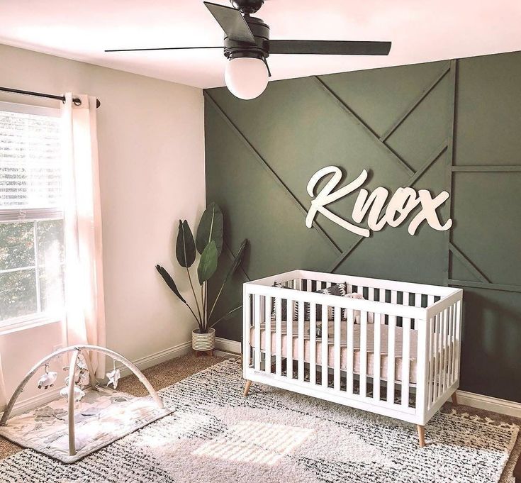 a baby's room with a crib, rocking chair and large green wall