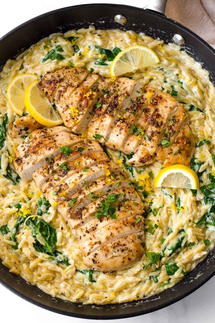 chicken and pasta in a skillet with lemons, spinach and parsley