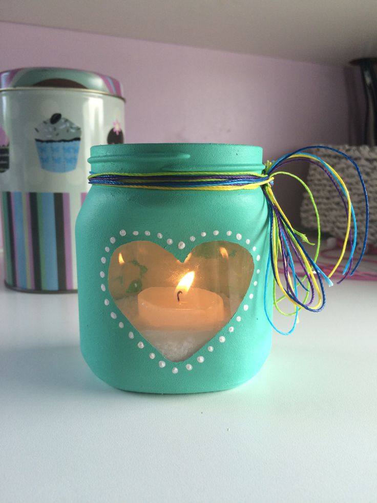 a blue mason jar with a lit candle in the shape of a heart on it