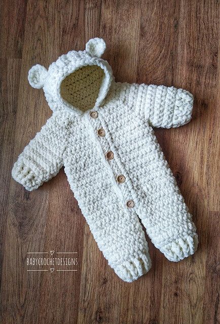 a crocheted white bear coat laying on top of a wooden floor