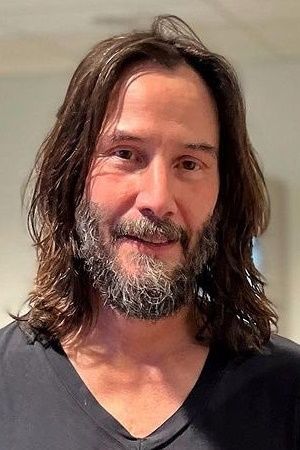 a man with long hair and a beard wearing a v - neck t - shirt