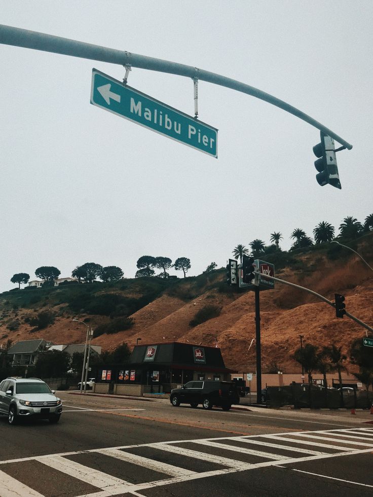 a street sign that reads malbu pie on the side of a hill with trees in the background