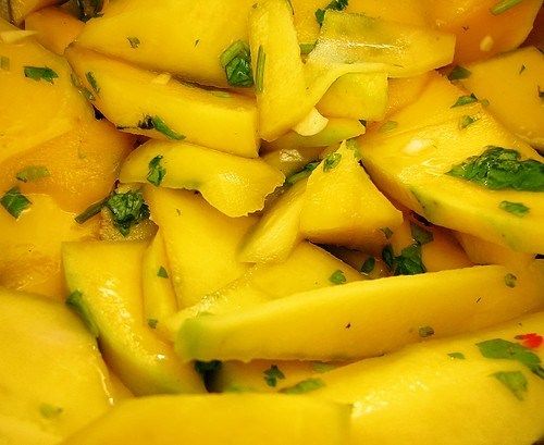 a close up view of yellow fruit with green leafy toppings on it's surface