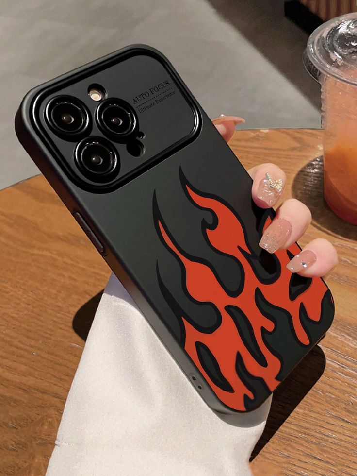 a woman is holding up her phone case with flames on the back and black sides