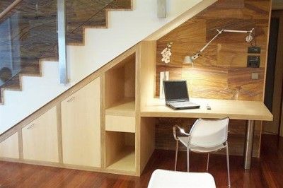 a laptop computer sitting on top of a desk next to a stair case in a room