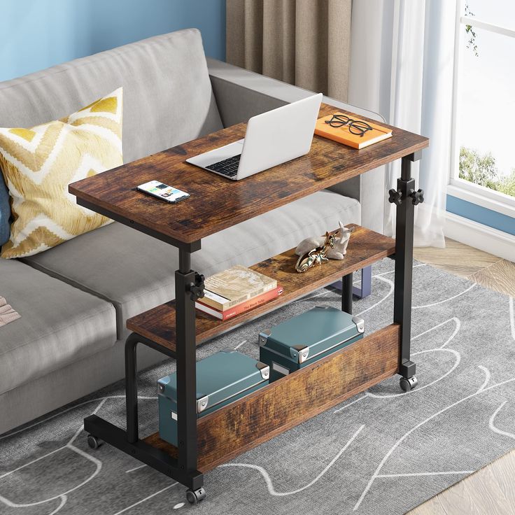 a laptop computer sitting on top of a wooden table next to a gray couch in a living room