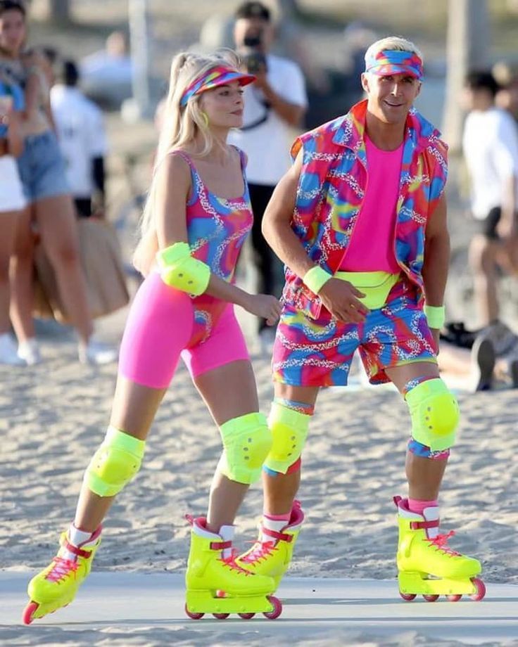 two people on roller skates with neon colored clothing and headbands at the beach