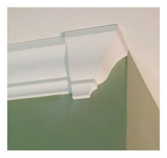 the corner of a room with green walls and white molding on the wall above it