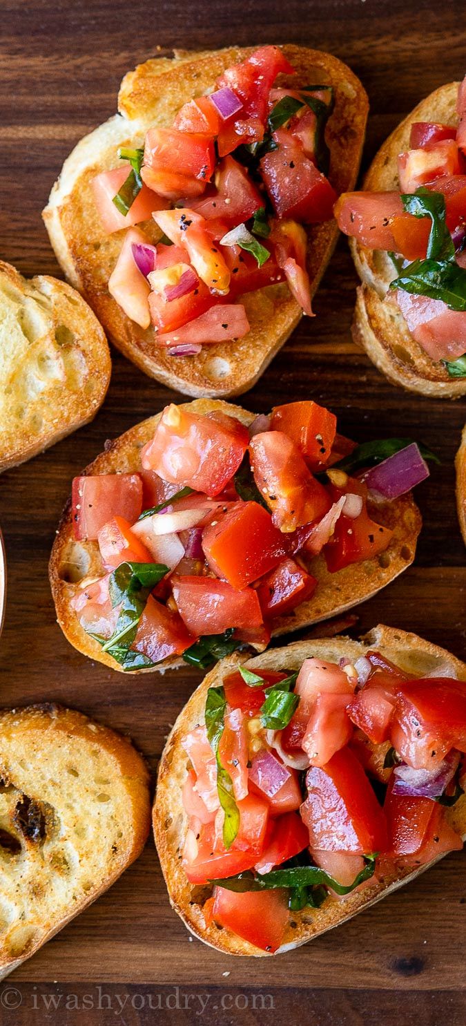 several pieces of bread with tomatoes and other toppings on them sitting on a wooden surface