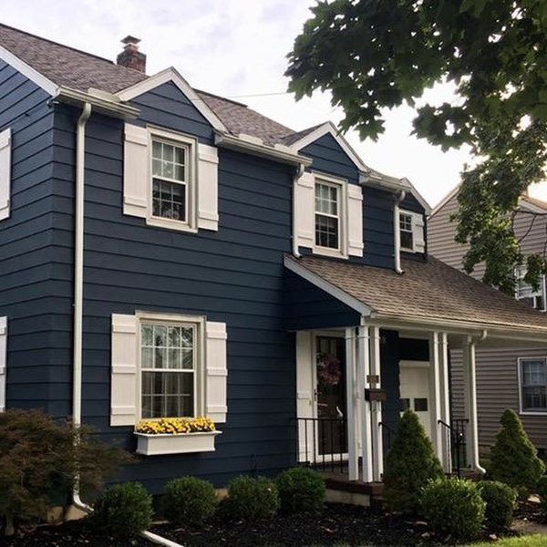 a blue house with white shutters on the front and side windows is pictured in this image