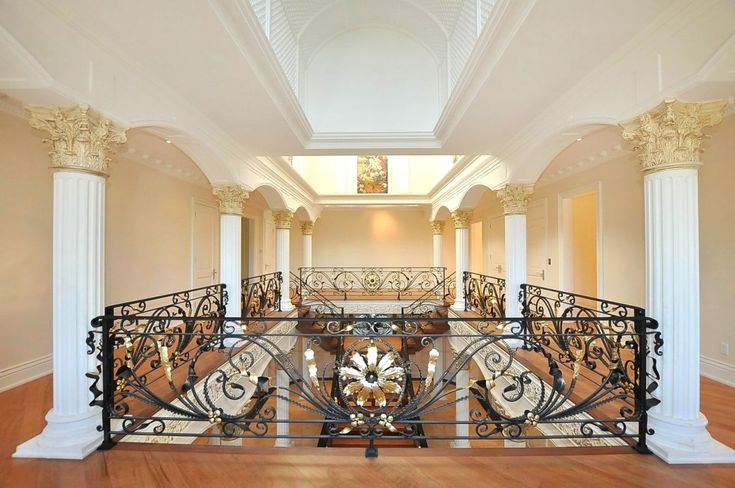 an ornate iron railing in the middle of a room with wood floors and white columns