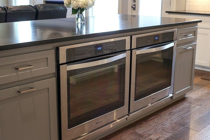 a kitchen with stainless steel appliances and white cabinets in the center, along with an island that has flowers on it