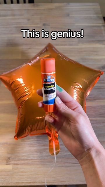 someone is holding an orange spray bottle in front of a star shaped balloon that says, this is genius