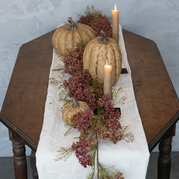 a table topped with pumpkins and flowers on top of a white cloth covered table