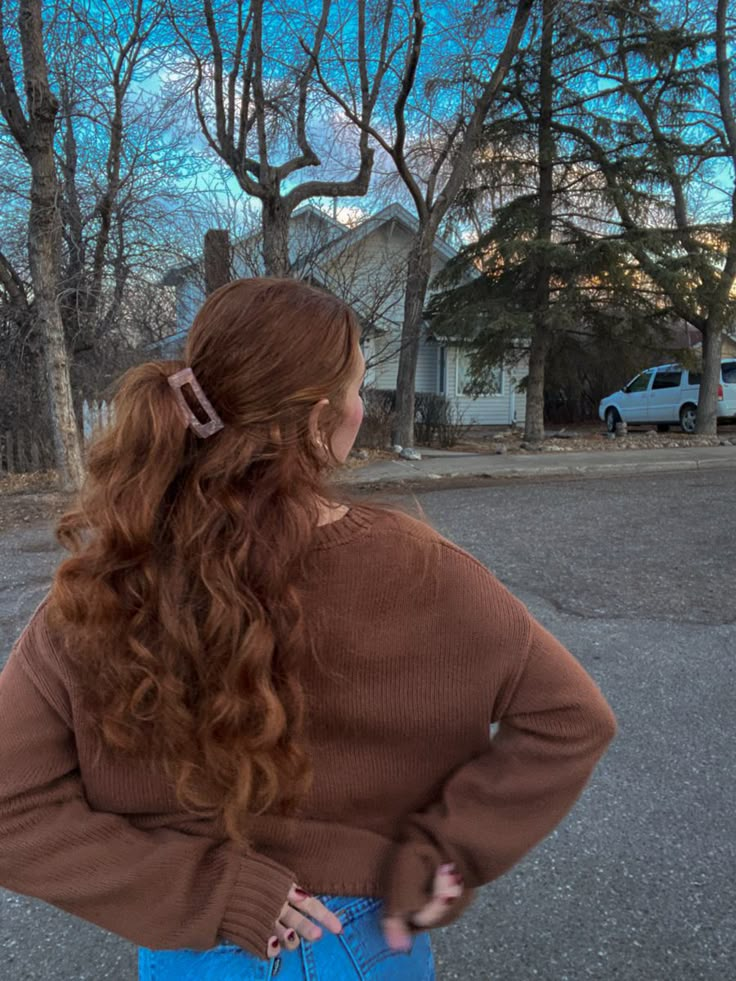 a picture of a womens back. she is wearing a brown cardigan and you can see her hands behind her back, she has on red nail polish. she has long wavy red hair pulled in a half up half down type style with a small pink claw clip. in the background you can see trees and a house Naturally Wavy Red Hair, Prom Dresses Ginger Hair, Wavy Red Hair Natural, Redhead Character Inspiration, Long Red Hair Aesthetic, Long Curly Ginger Hair, Auburn Hair Aesthetic, Curly Red Hair Aesthetic, Auburn Wavy Hair