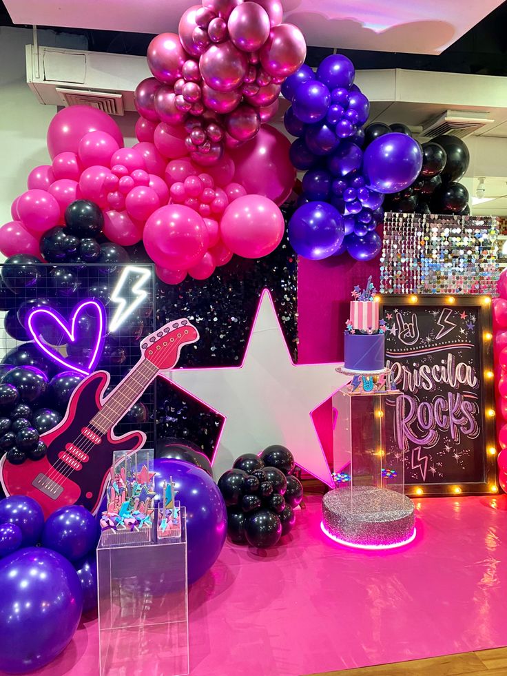 a pink and purple birthday party with balloons, guitar, stars, and other decorations