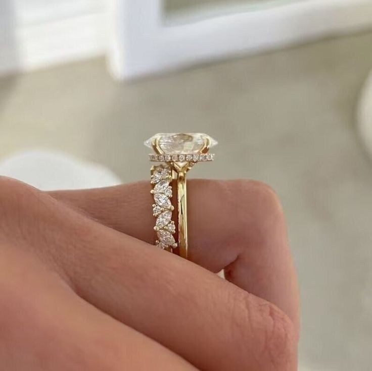 a close up of a person's hand holding a diamond ring