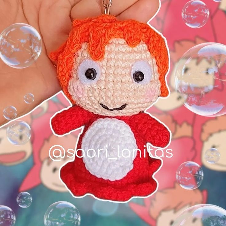 a crocheted keychain with a red haired girl on it's face