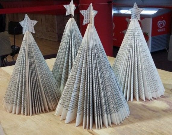 three folded paper christmas trees sitting on top of a wooden table