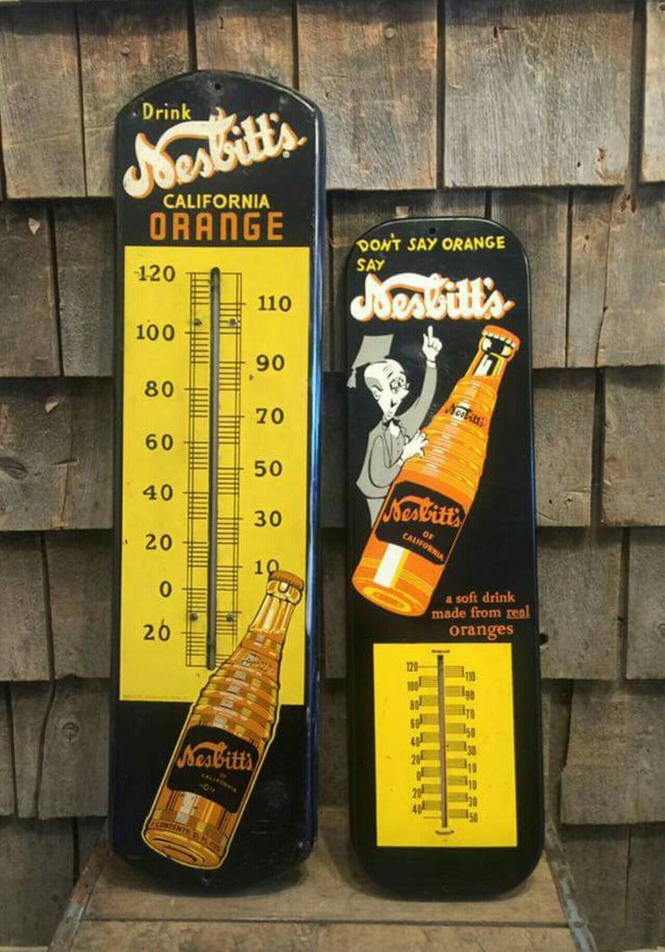 two thermometers are sitting next to each other on a wooden table with an advertisement