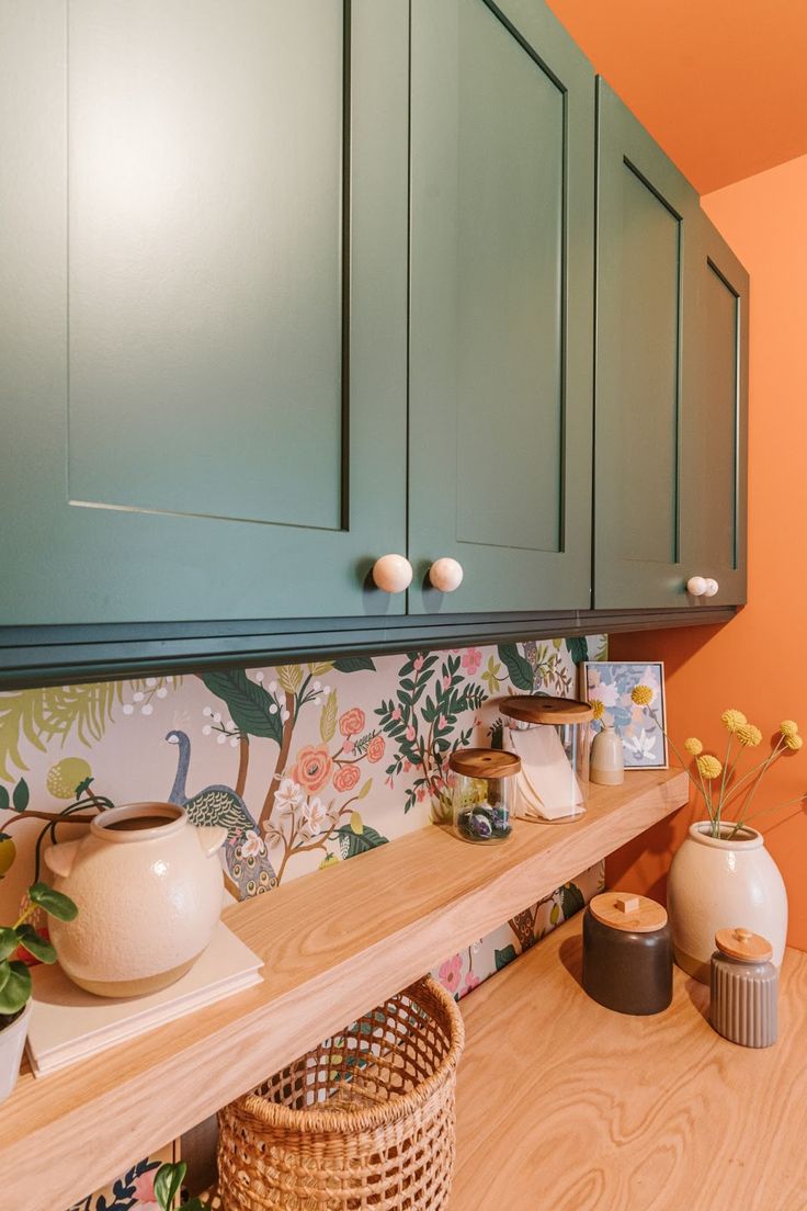 a kitchen with green cabinets and wooden flooring next to a basket on the counter