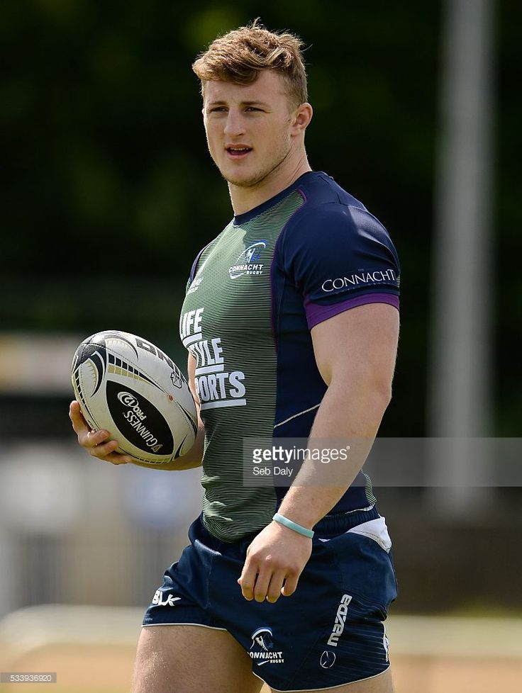 a man holding a rugby ball on top of a field