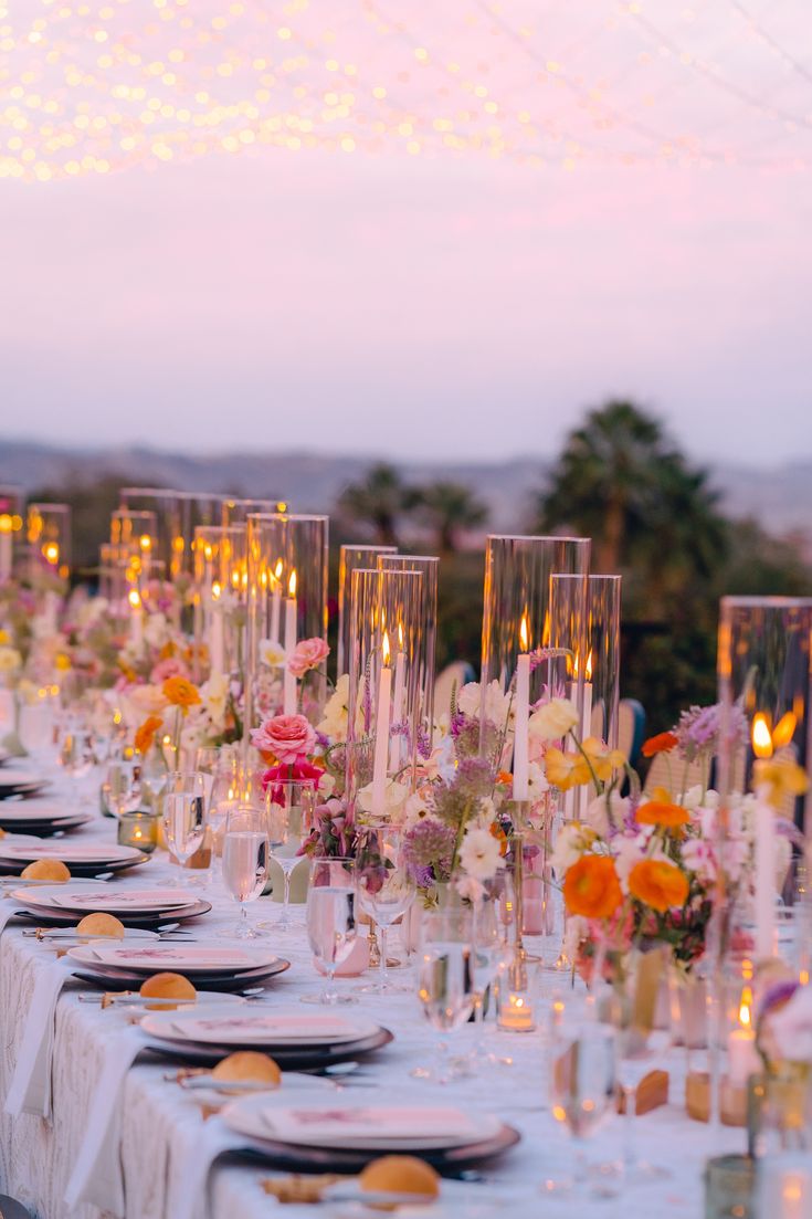 a long table is set with plates and candles