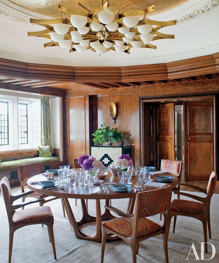 a dining room table and chairs in front of a large window with wooden paneling