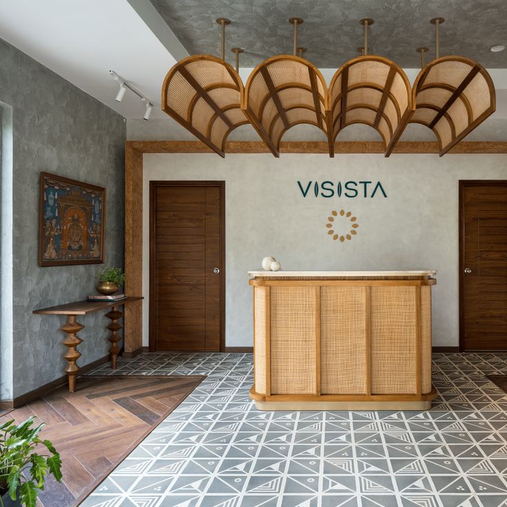 the front desk of a hotel lobby with wooden doors and decorative artwork on the walls