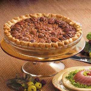 there is a pie with pecans on top and other desserts in the background