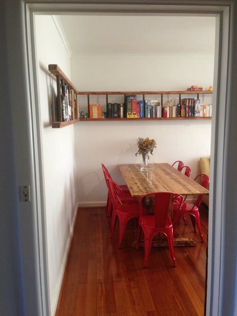 a dining room table with red chairs and bookshelves