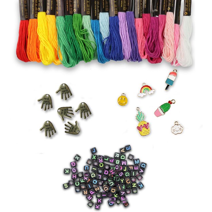 a bunch of different colored beads and charms on a white surface with some scissors in the background