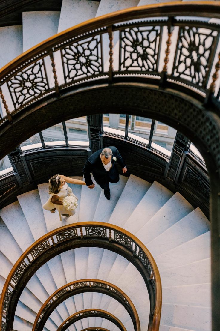 a man and woman are standing on the top of a spiral staircase