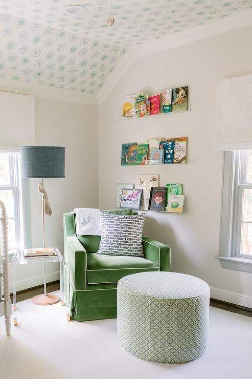 a green chair and ottoman in a small room with white carpeted flooring, two windows, and wallpaper on the walls