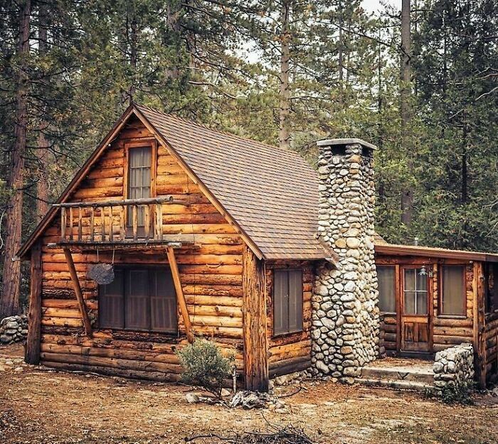 a log cabin in the woods with a stone chimney