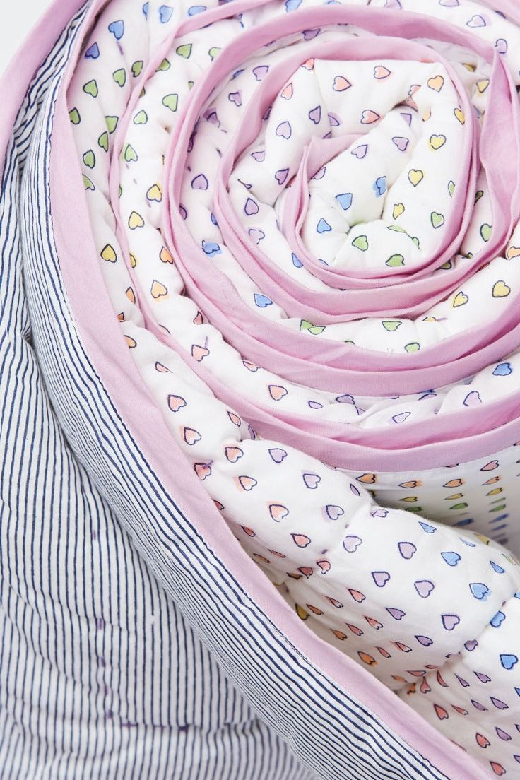 the pink and white scarf is folded up on top of striped shirting, with hearts all over it