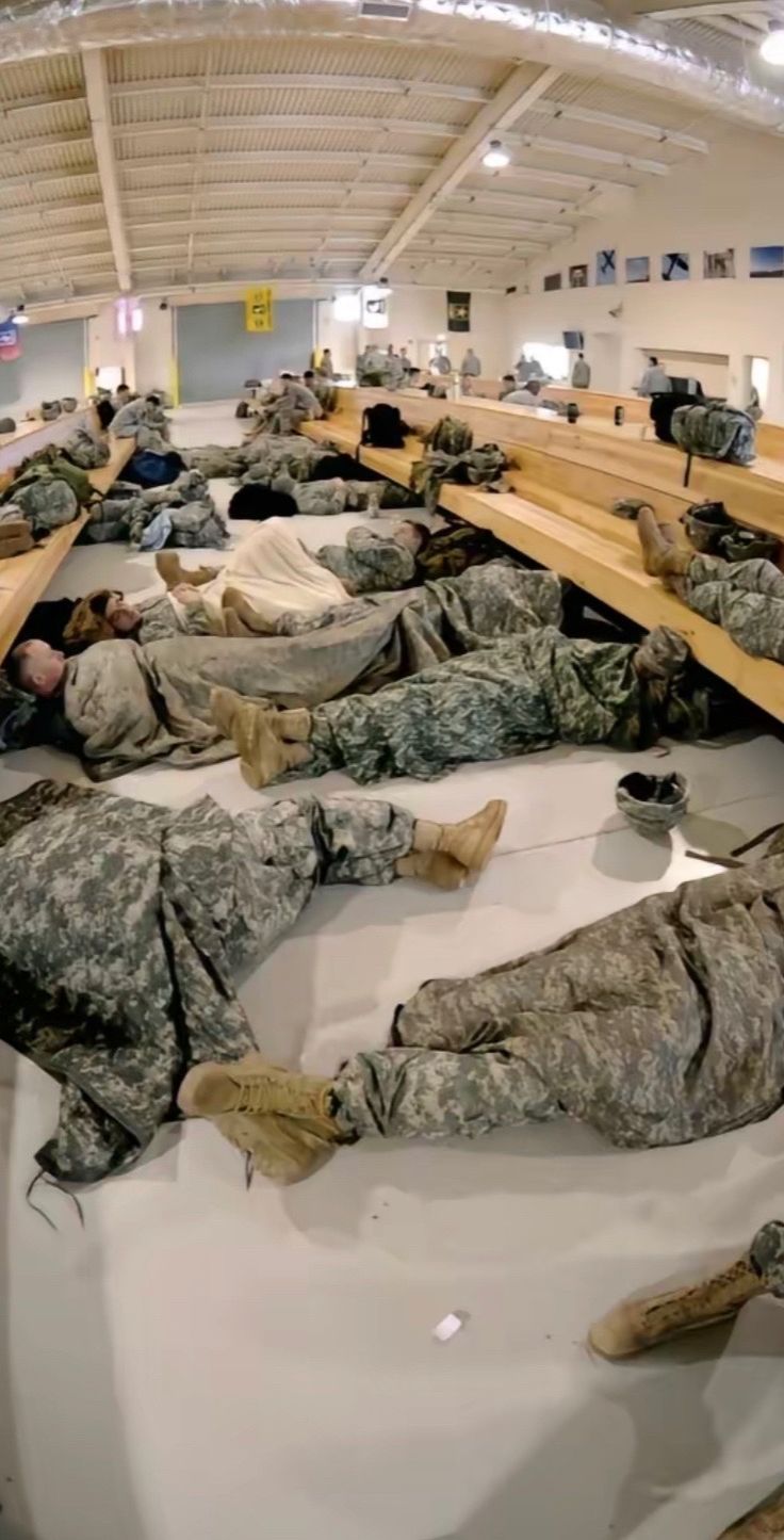 many soldiers are sleeping on benches in an airport