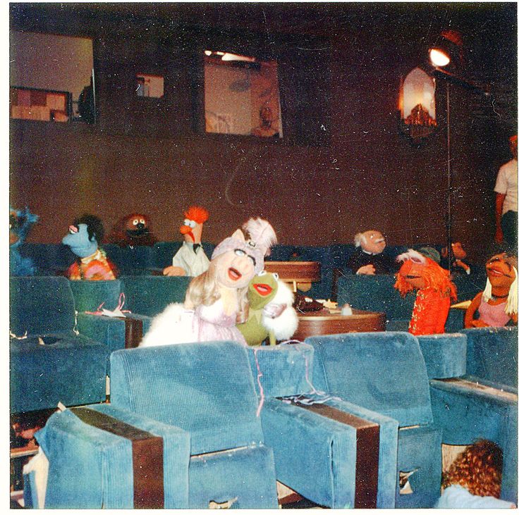 an old photo of some people sitting in blue chairs with stuffed animals on their backs