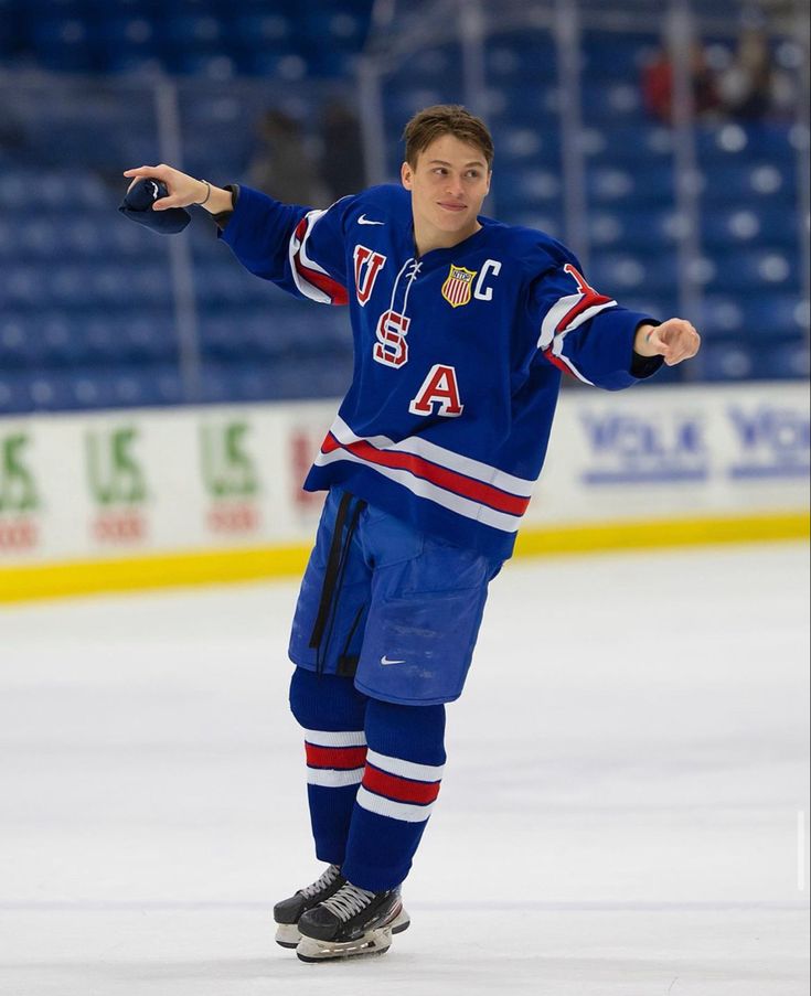 a young man skating on an ice rink with his arms out and one hand in the air