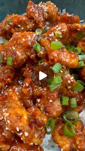 chicken with sesame seeds and green onions on top of rice in a blue bowl, ready to be eaten