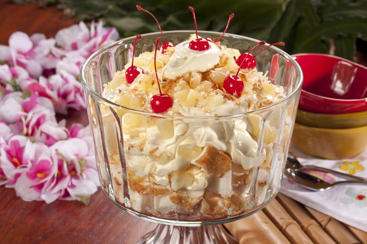 a glass bowl filled with food on top of a wooden table next to pink flowers