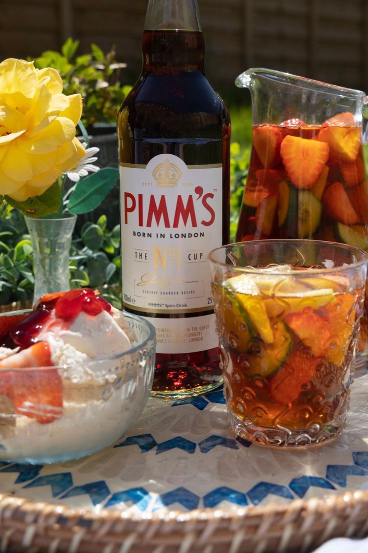 a table topped with glasses filled with fruit and ice cream next to a bottle of pimm's