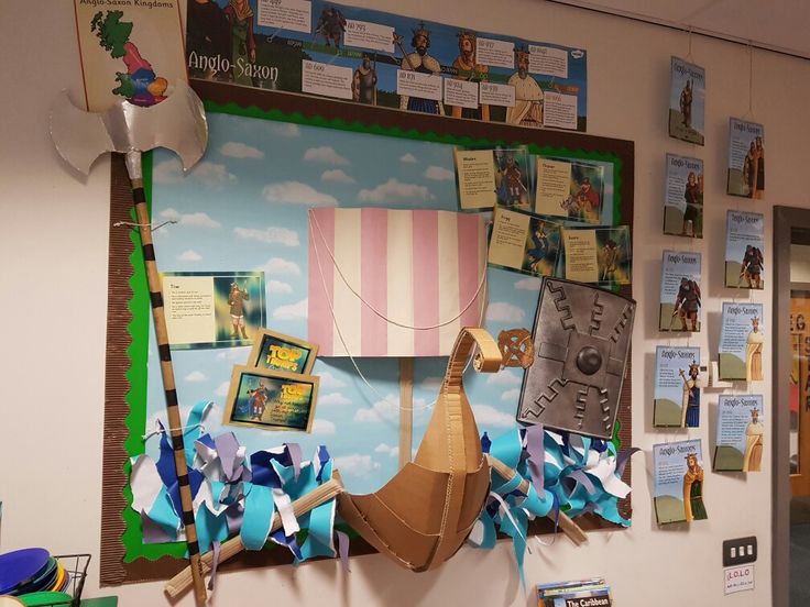 a bulletin board with paper decorations and pictures on the wall in an elementary classroom setting