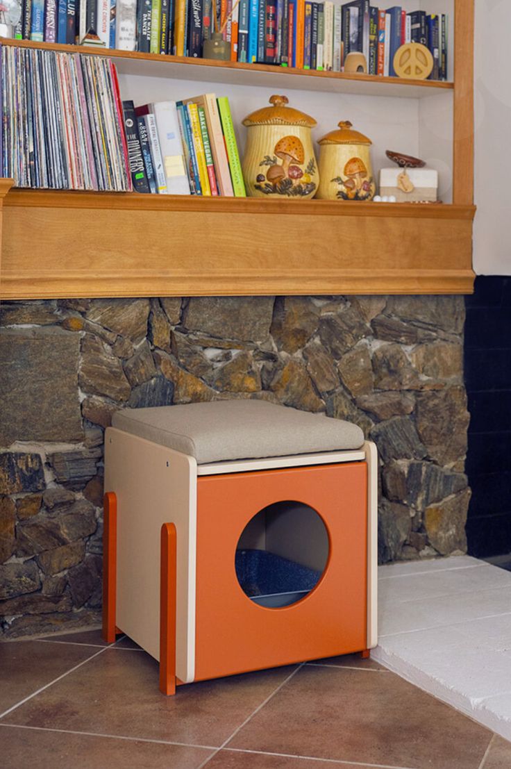 an orange box sitting on the floor in front of a book shelf filled with books