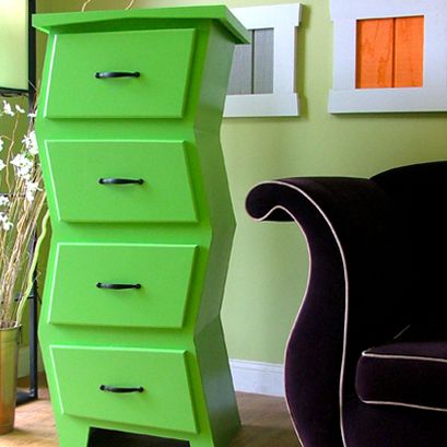 a green chest of drawers next to a black chair