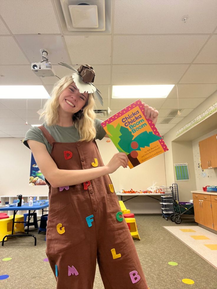 a woman in brown overalls holding up a book