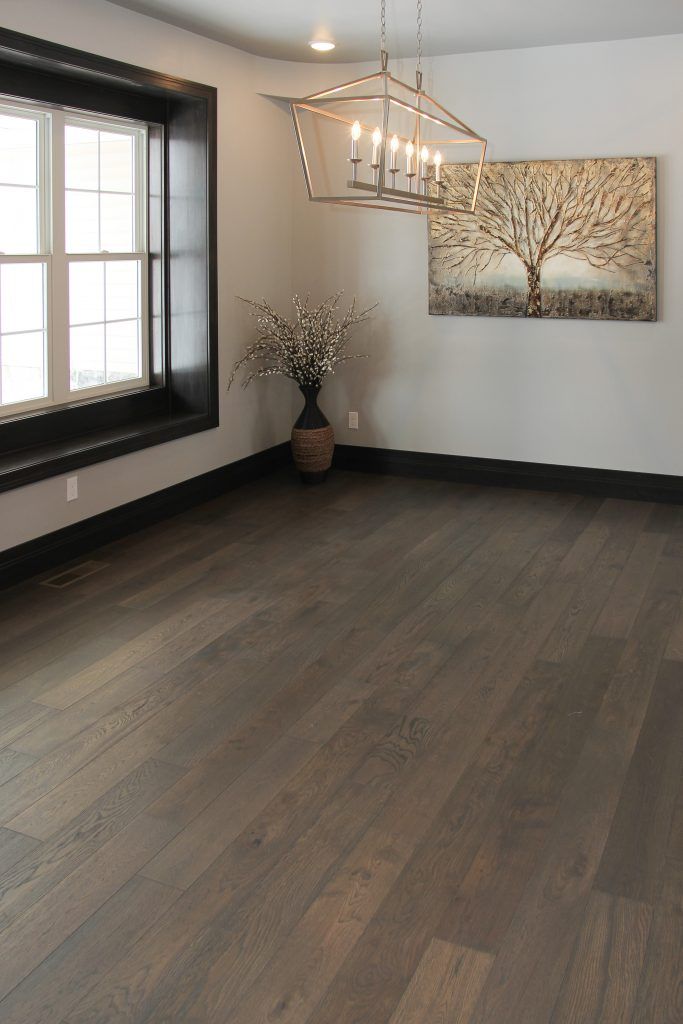 an empty room with wood flooring and chandelier hanging from the ceiling in front of a window